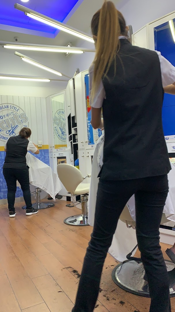 Two stylists working inside a kcuts hair salon, with chairs and mirrors visible.