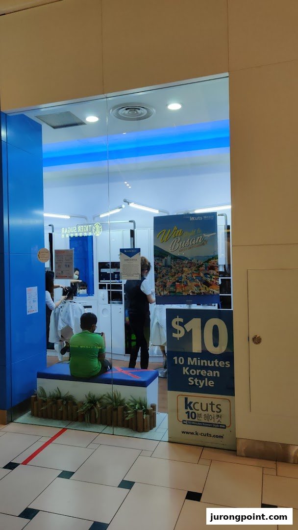 The kcuts shop front features a blue and white design, with customers inside and promotional signage.