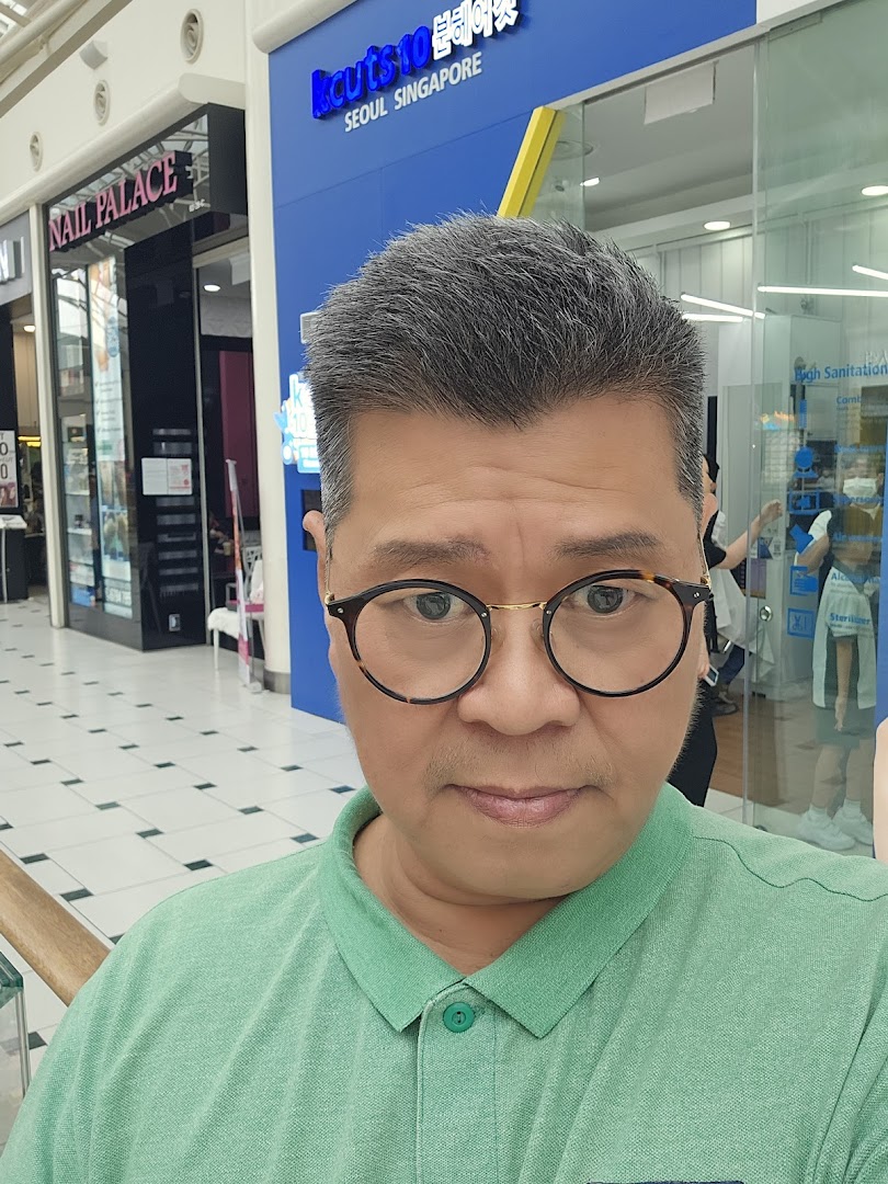 A person stands in front of the kcuts shop entrance within a shopping mall.