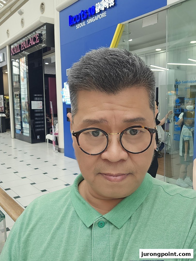 A person stands in front of the kcuts shop entrance within a shopping mall.