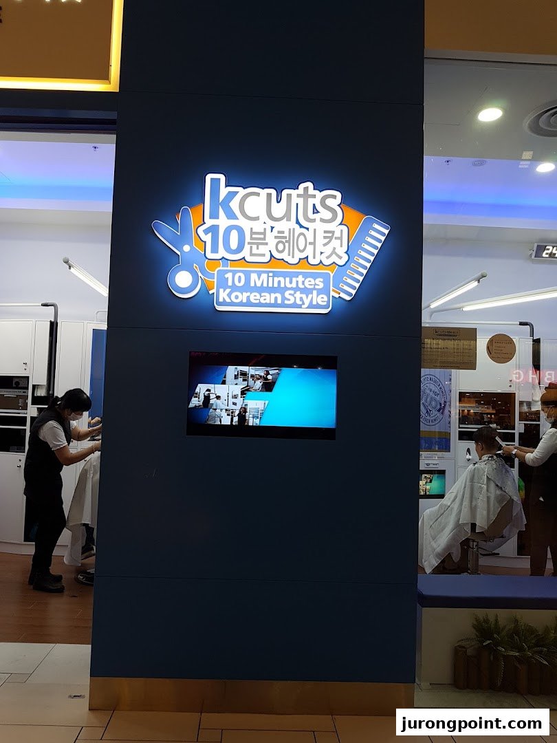 The kcuts shopfront features its illuminated logo and a glimpse of customers receiving haircuts inside.