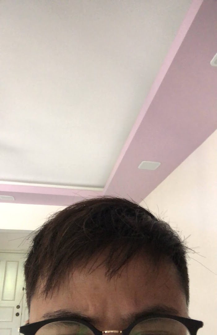 A close-up of a person's head, showing hair and glasses, looking towards a ceiling.
