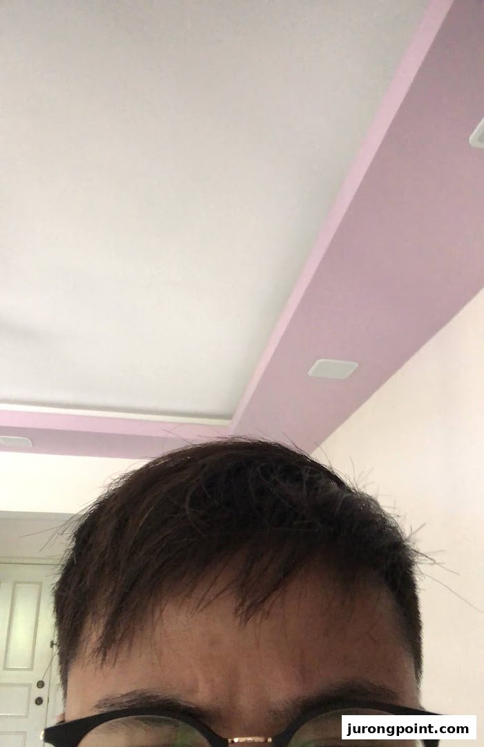 A close-up of a person's head, showing hair and glasses, looking towards a ceiling.