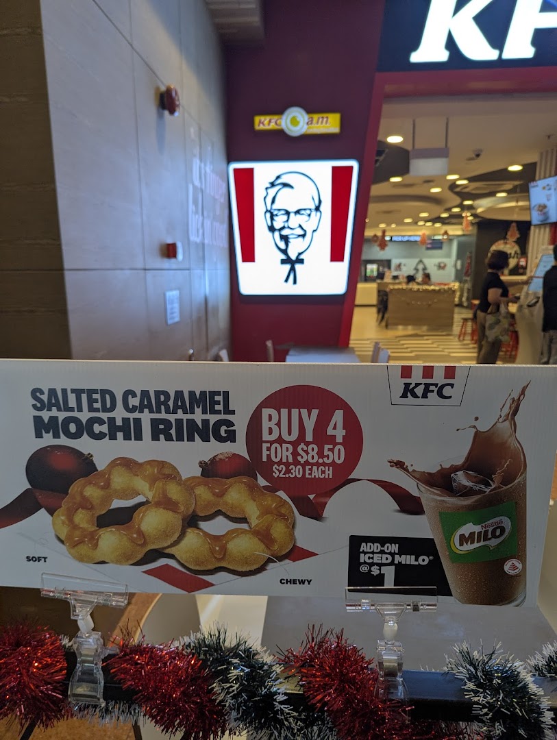 A promotional display for KFC's Salted Caramel Mochi Ring and Iced Milo at the shop entrance.