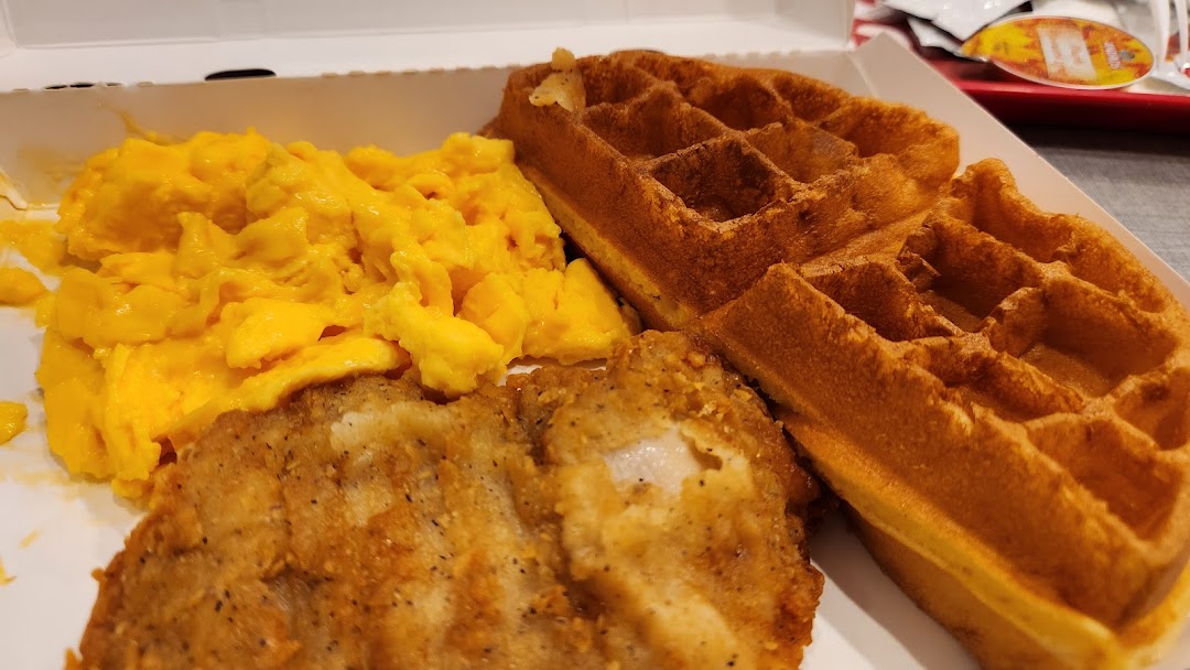 A close-up of KFC's fried chicken, waffles, and scrambled eggs in a takeout box.