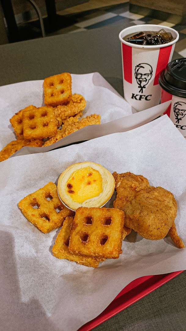 A delicious spread of KFC fried chicken, waffle fries, an egg tart, and refreshing drinks.