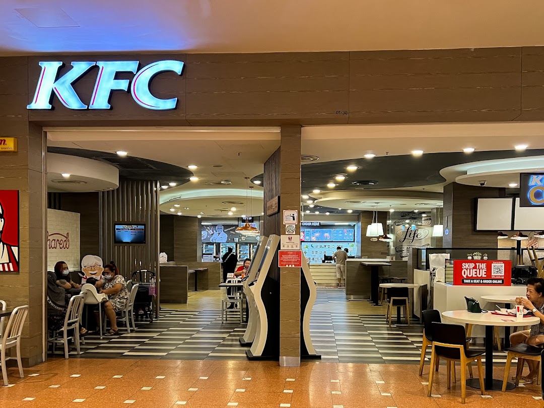 The inviting entrance of a KFC restaurant in a shopping mall, showcasing its interior and seating.
