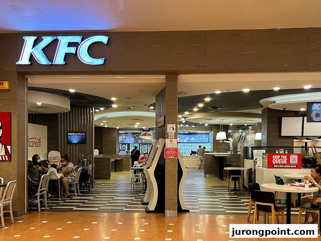 The inviting entrance of a KFC restaurant in a shopping mall, showcasing its interior and seating.