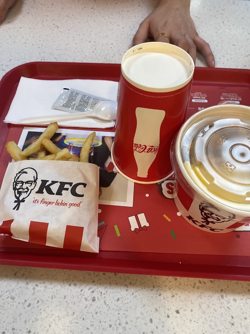 A KFC meal on a red tray, featuring fries, a drink, and a dessert.