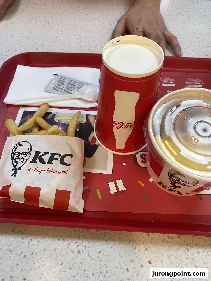 A KFC meal on a red tray, featuring fries, a drink, and a dessert.