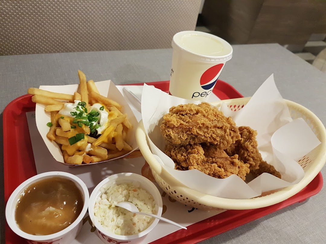 A tray featuring KFC fried chicken, loaded fries, coleslaw, gravy, and a Pepsi drink.