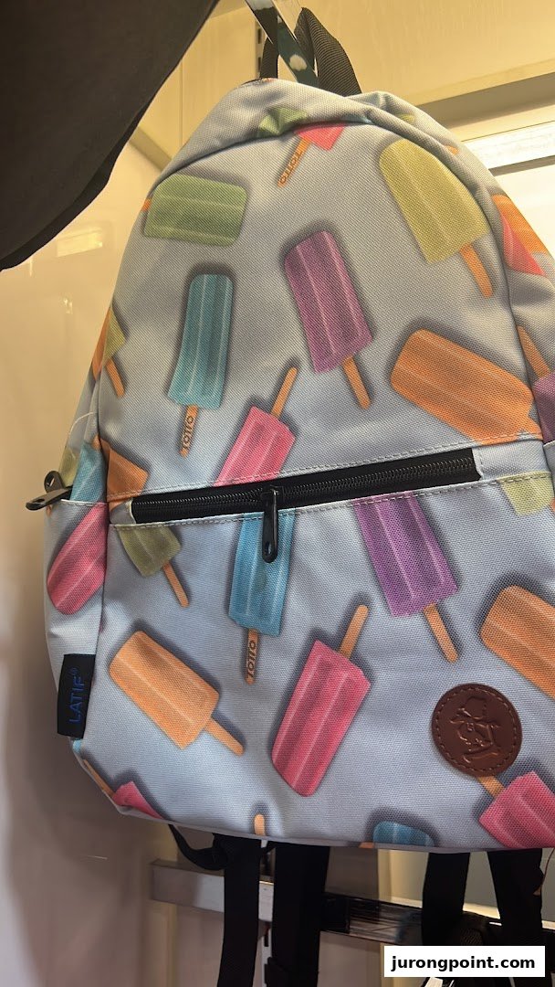 A colorful backpack featuring a playful popsicle pattern, displayed in a retail setting.