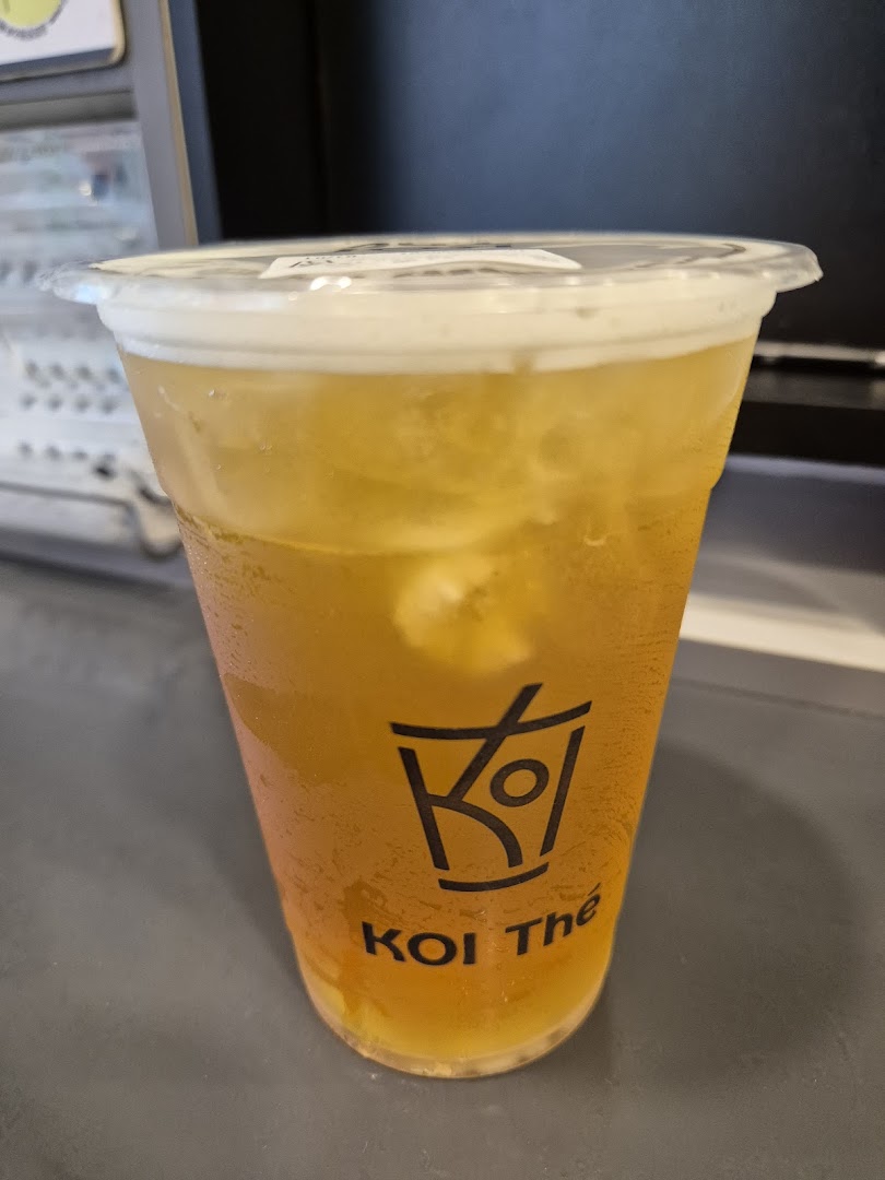 A refreshing iced tea with a foam topping in a clear KOI Thé branded cup.