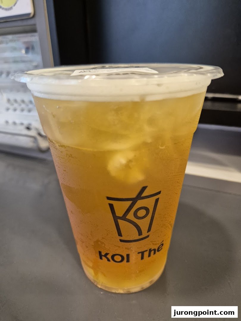 A refreshing iced tea with a foam topping in a clear KOI Thé branded cup.