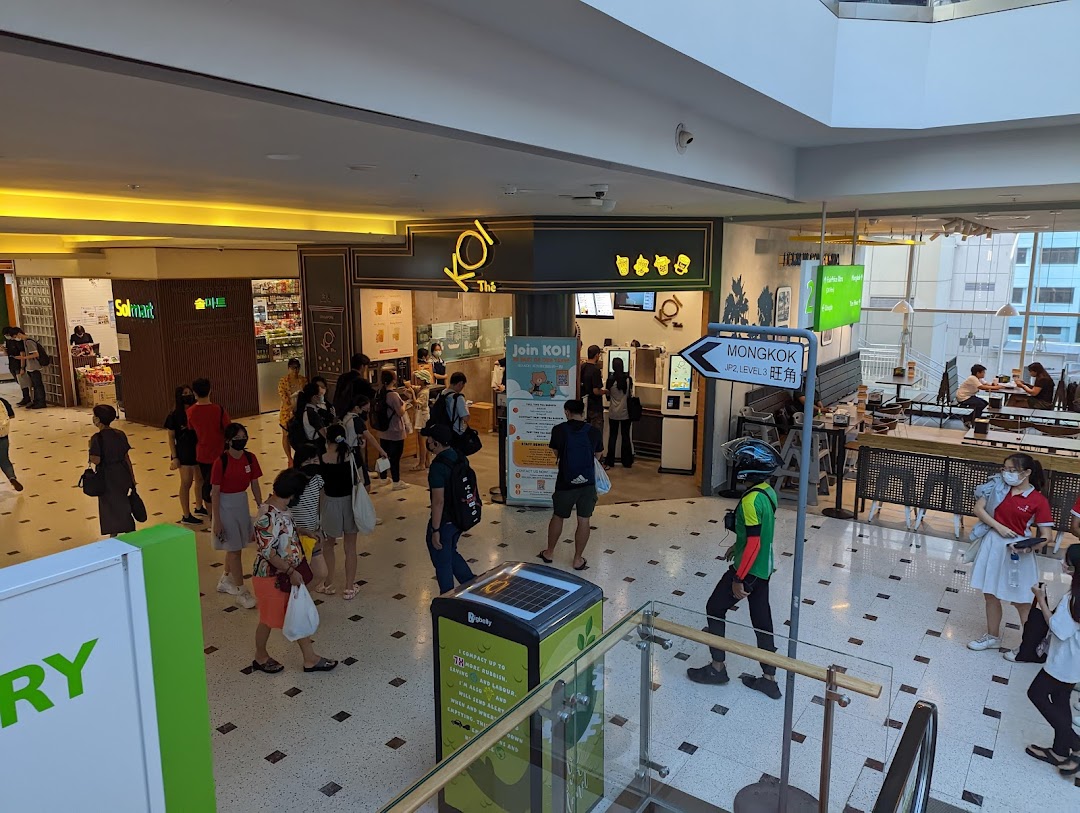 A bustling view of the KOI Thé shop entrance in a mall, with customers queuing.