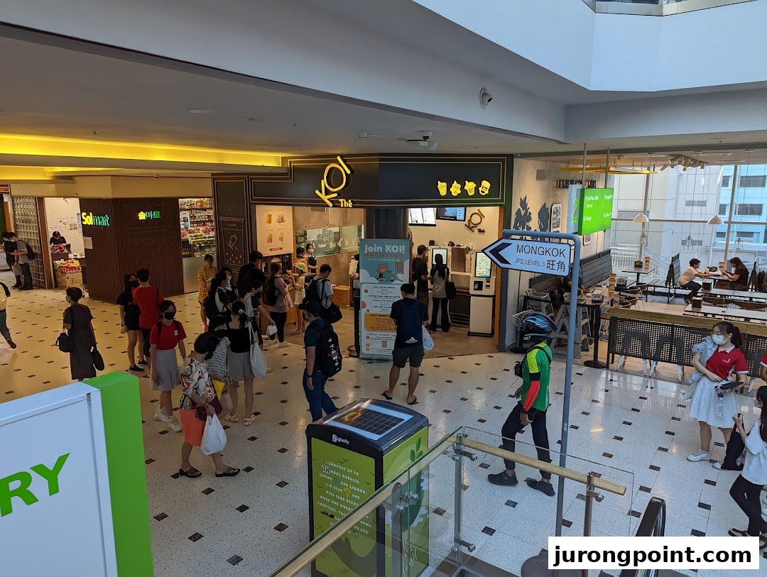 A bustling view of the KOI Thé shop entrance in a mall, with customers queuing.