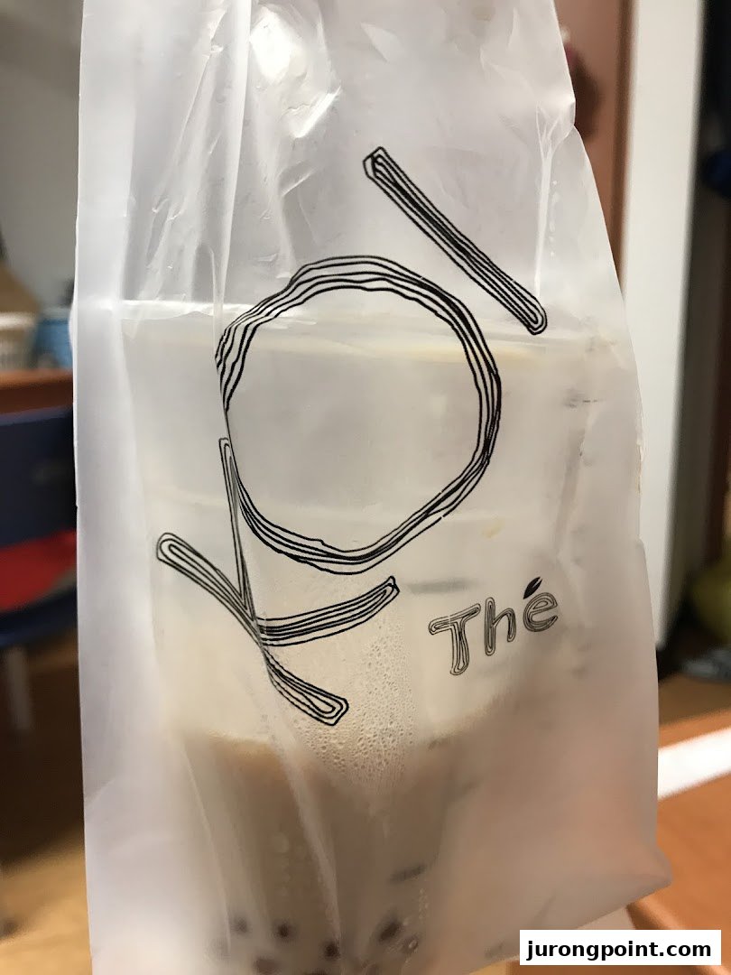 A KOI Thé bubble tea drink in a branded translucent plastic bag, showcasing the beverage inside.