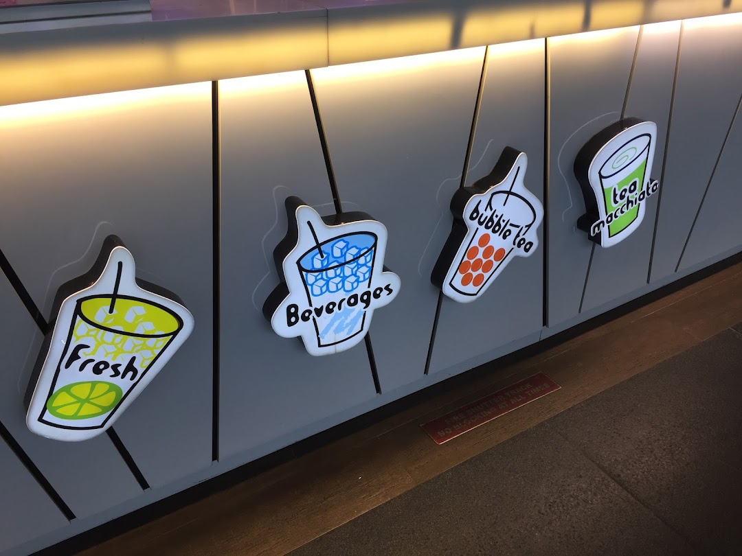 Decorative signs for fresh drinks, beverages, bubble tea, and tea macchiato on a shop counter.