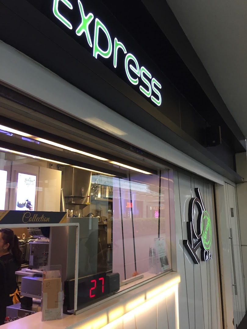 A view of the KOI Thé Express shop front, featuring its neon sign and counter area.