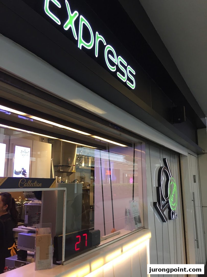 A view of the KOI Thé Express shop front, featuring its neon sign and counter area.