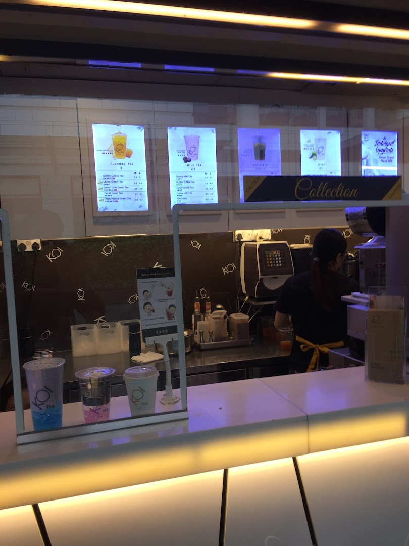 Interior view of KOI Thé bubble tea shop counter with staff and menu displays.