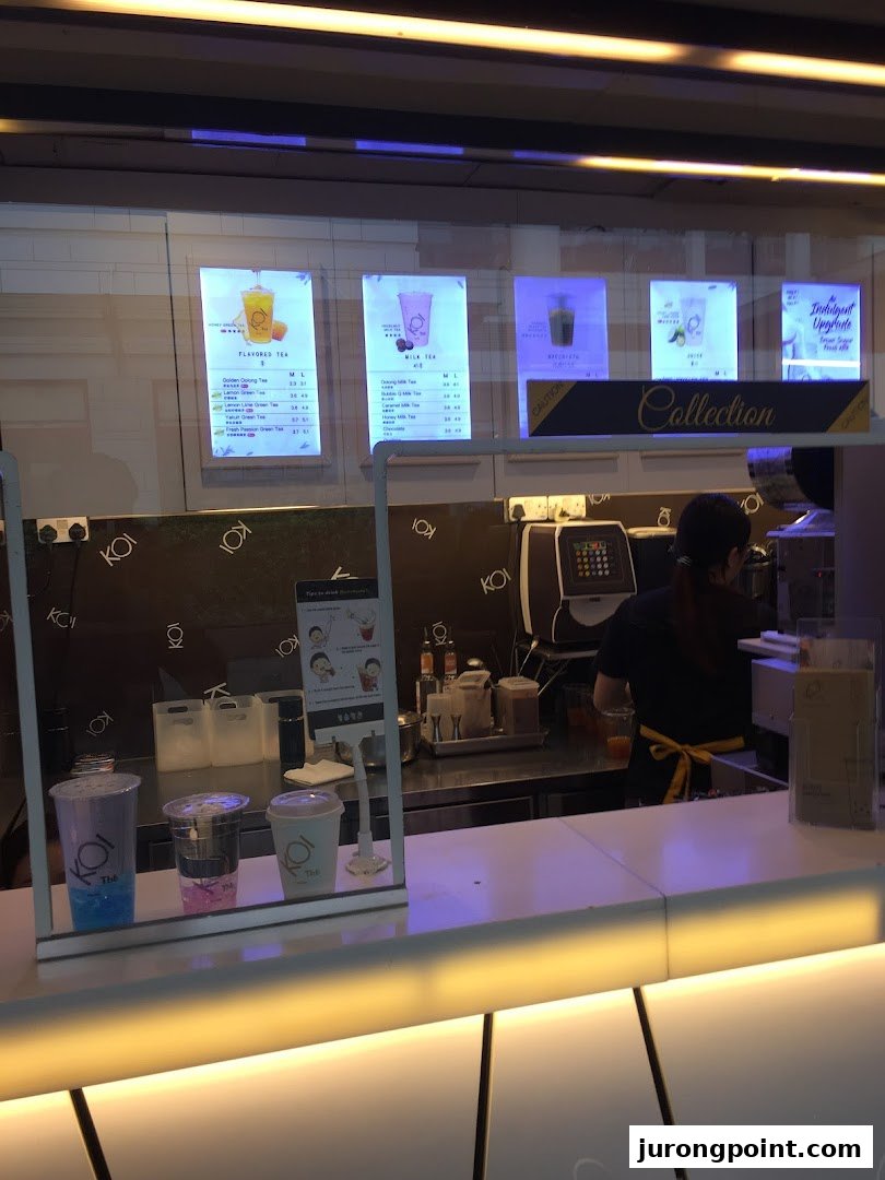 Interior view of KOI Thé bubble tea shop counter with staff and menu displays.