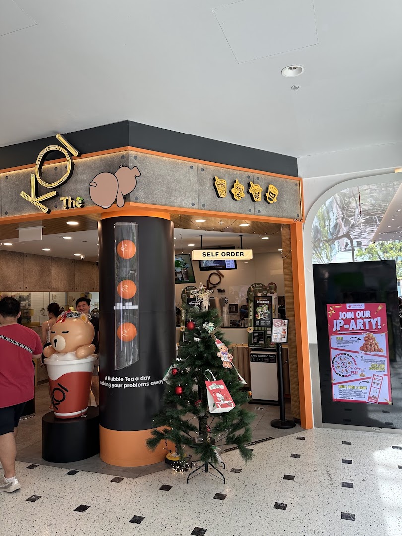 The inviting shop front of KOI Thé bubble tea, featuring a large bear mascot and festive Christmas decorations.