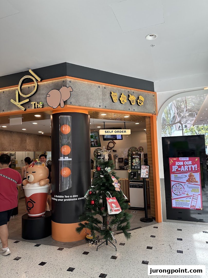 The inviting shop front of KOI Thé bubble tea, featuring a large bear mascot and festive Christmas decorations.