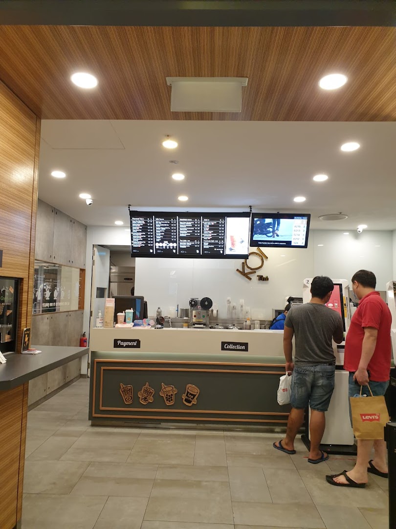 Interior view of KOI Thé with customers at the counter and digital menu boards displaying beverage options.