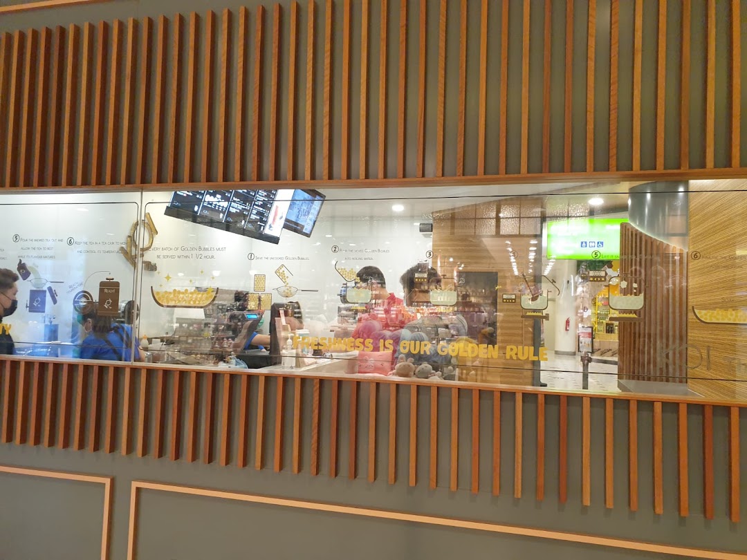 An interior view of KOI Thé, showcasing the preparation area and staff through a large glass window.