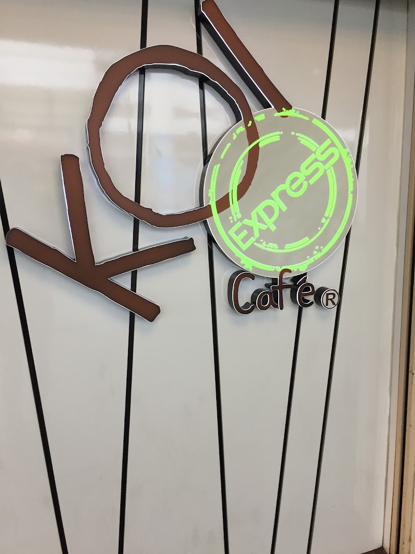 Close-up of the KOI Thé Express Café logo featuring stylized brown letters and a glowing green 'Express' sign.