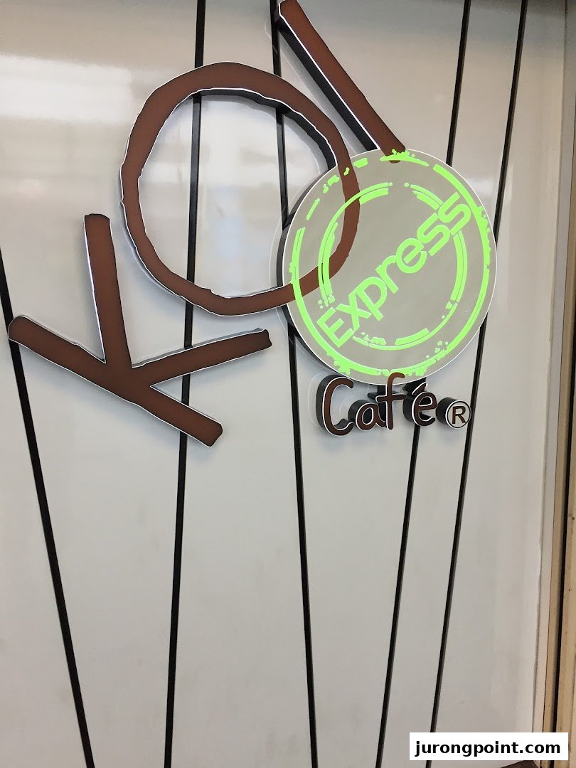 Close-up of the KOI Thé Express Café logo featuring stylized brown letters and a glowing green 'Express' sign.