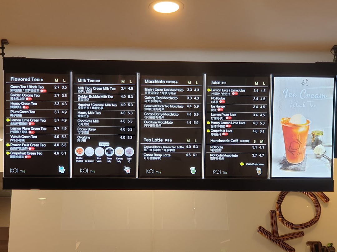 A brightly lit digital menu board displaying various bubble tea and beverage options at KOI Thé.