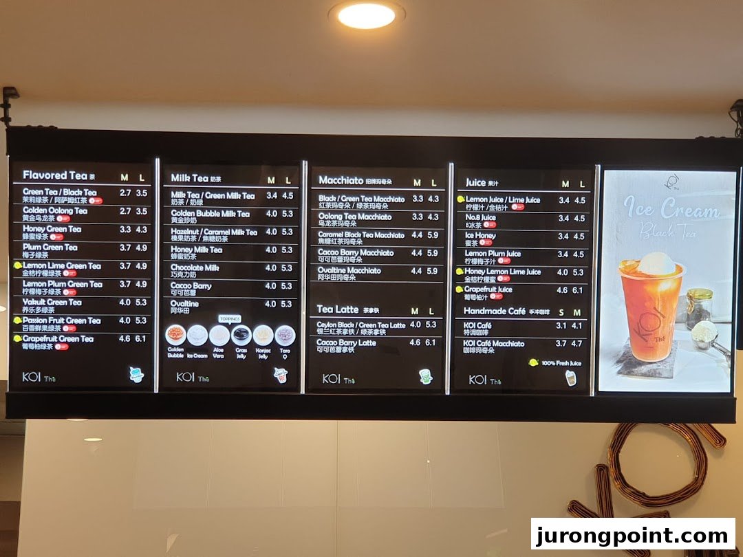 A brightly lit digital menu board displaying various bubble tea and beverage options at KOI Thé.