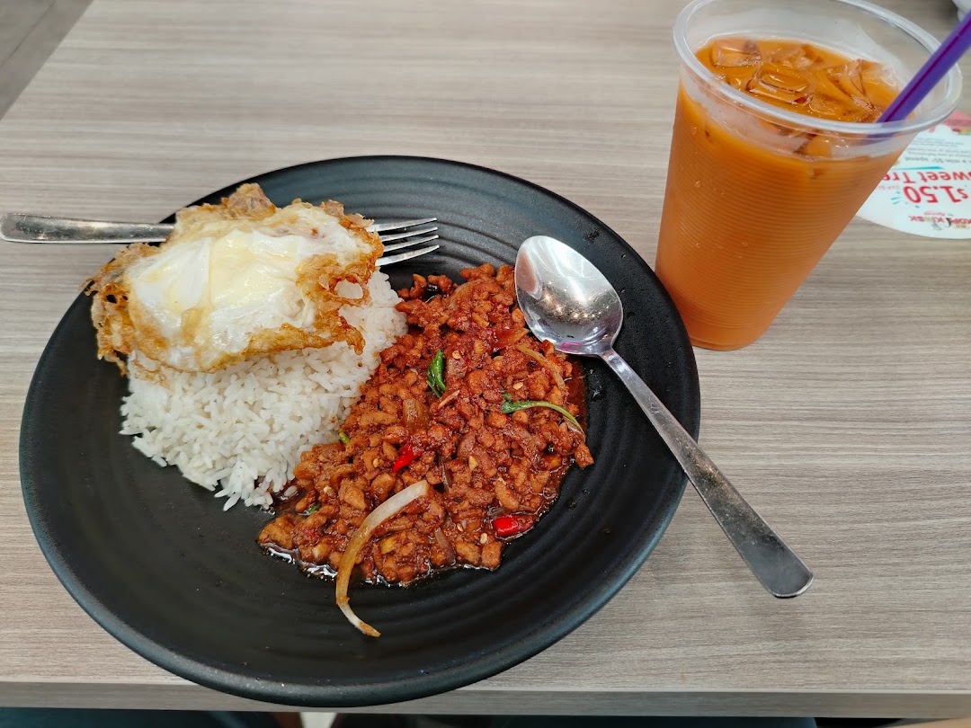 A plate of spicy minced meat with rice and a fried egg, served with an iced Thai milk tea.