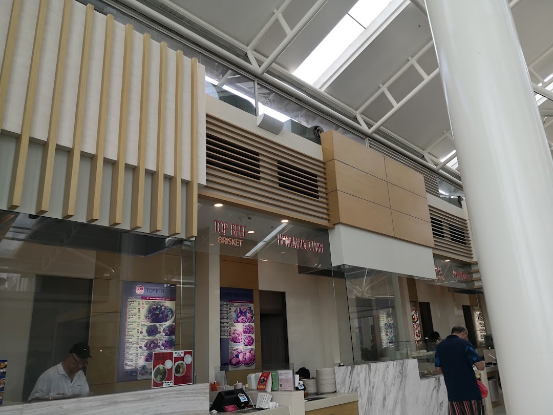 A bright interior view of a food stall within Kopitiam Food Hall, featuring menu displays and service counter.