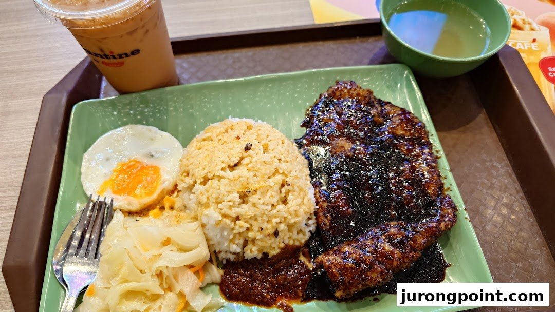 A delicious meal featuring grilled meat, rice, fried egg, and pickled vegetables, served with an iced drink.