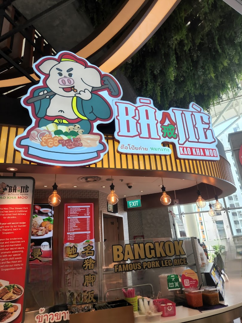 The vibrant storefront of Ba Jie Kao Kha Moo, a Thai pork leg rice stall, within a food hall.
