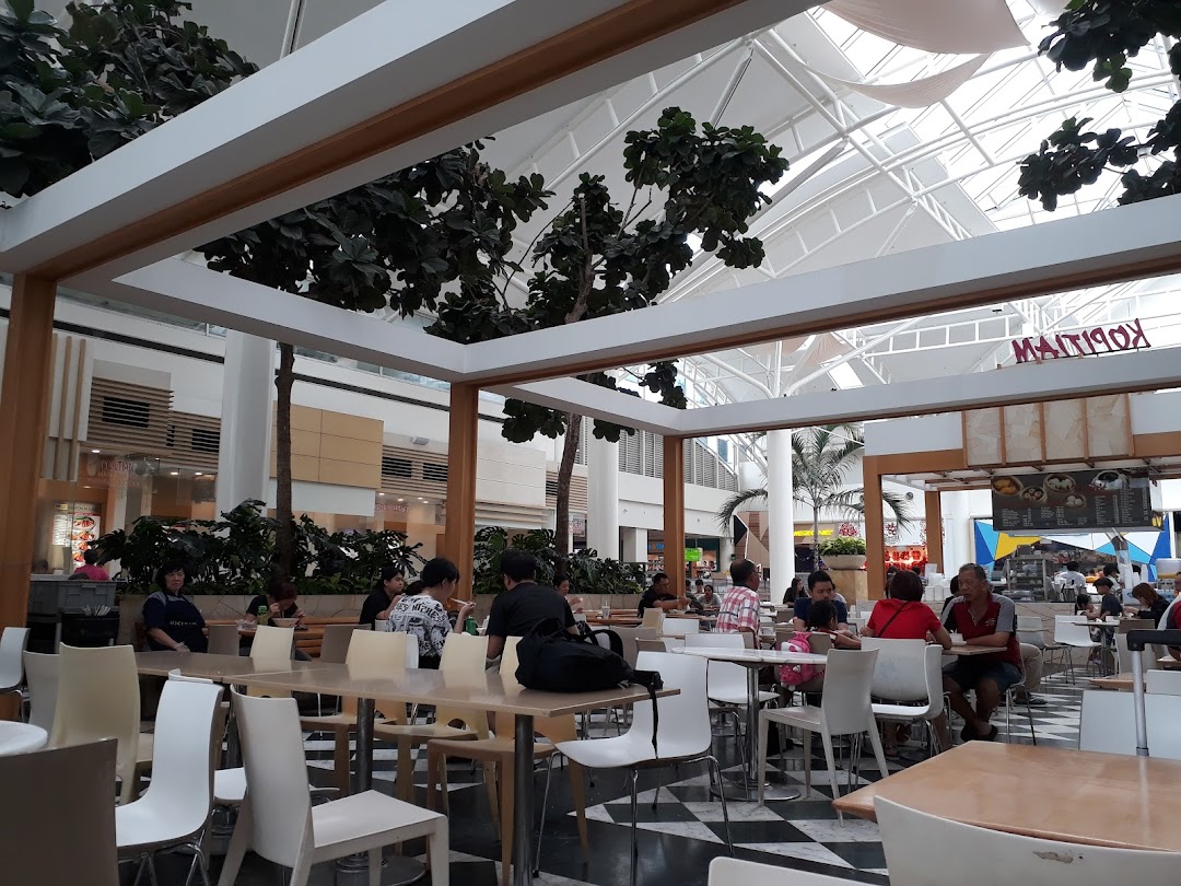 Diners enjoying meals in the spacious Kopitiam Food Hall with a bright, airy atmosphere.