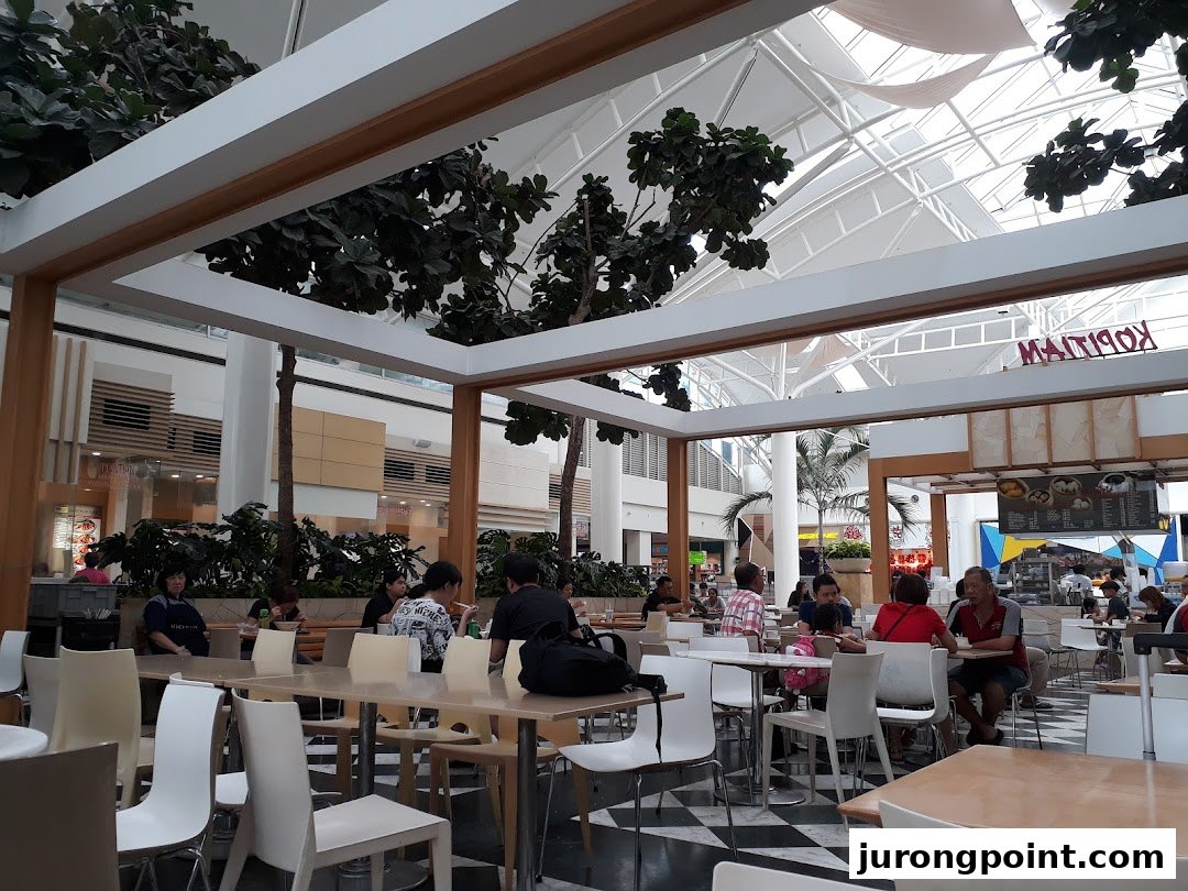 Diners enjoying meals in the spacious Kopitiam Food Hall with a bright, airy atmosphere.
