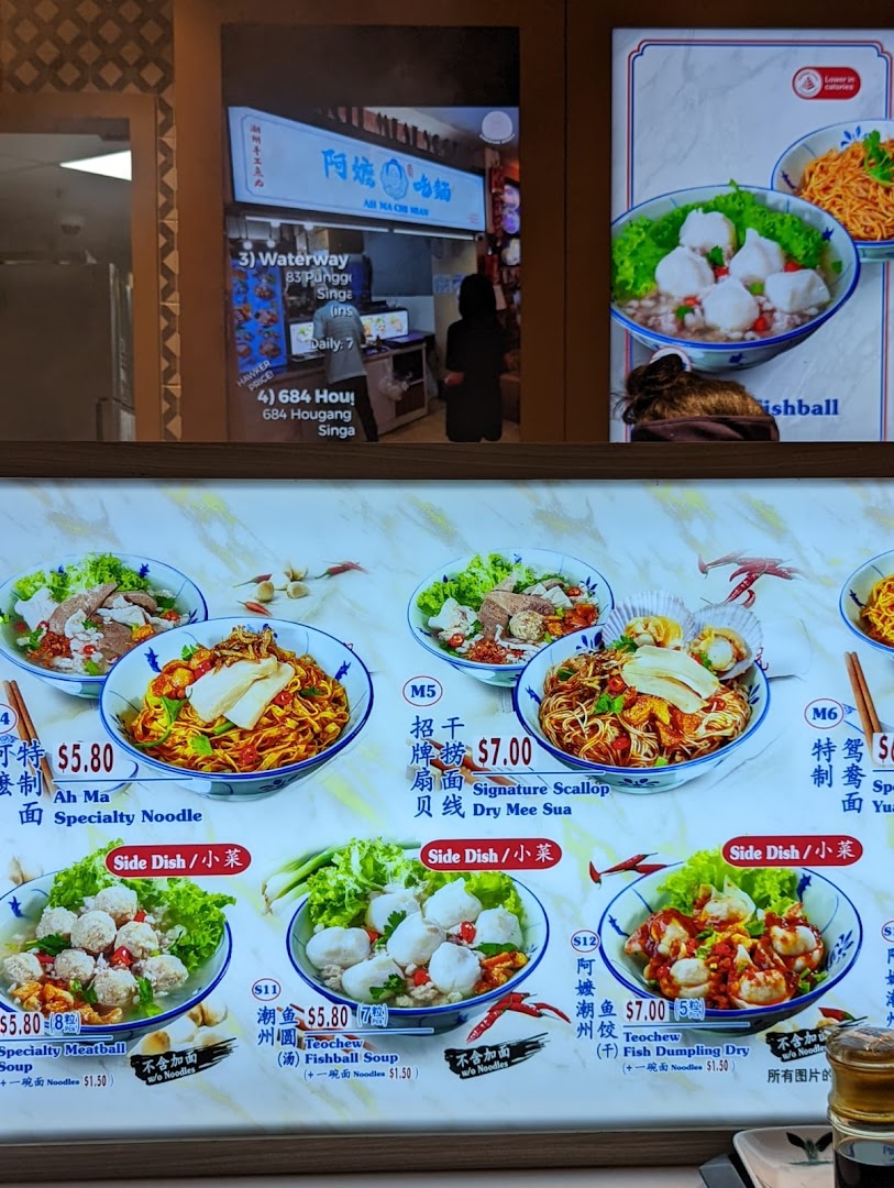 A vibrant menu board showcasing various noodle and soup dishes with prices at a food hall stall.