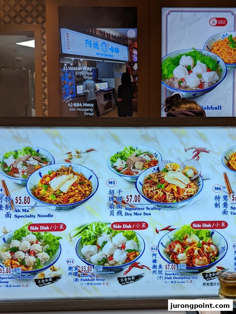 A vibrant menu board showcasing various noodle and soup dishes with prices at a food hall stall.