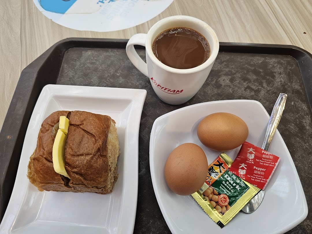 A traditional Kopitiam breakfast set with kaya toast, soft-boiled eggs, and a hot beverage.