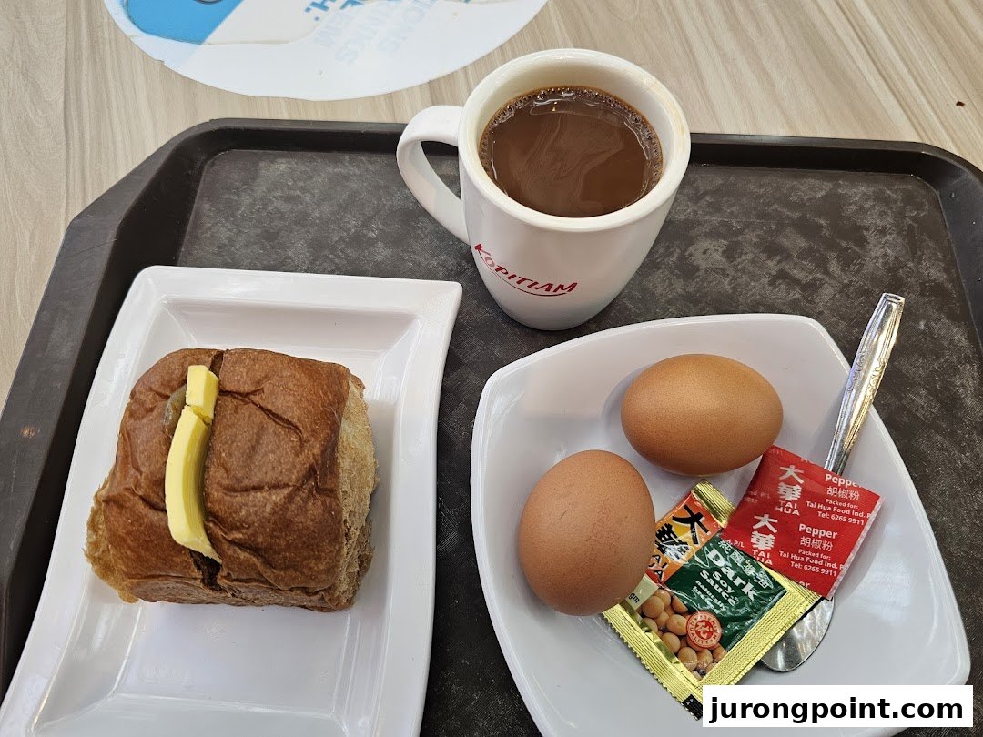 A traditional Kopitiam breakfast set with kaya toast, soft-boiled eggs, and a hot beverage.