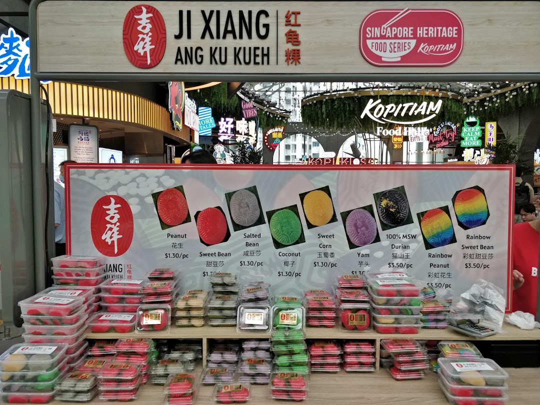 A vibrant display of traditional Ang Ku Kueh pastries with a detailed menu board.