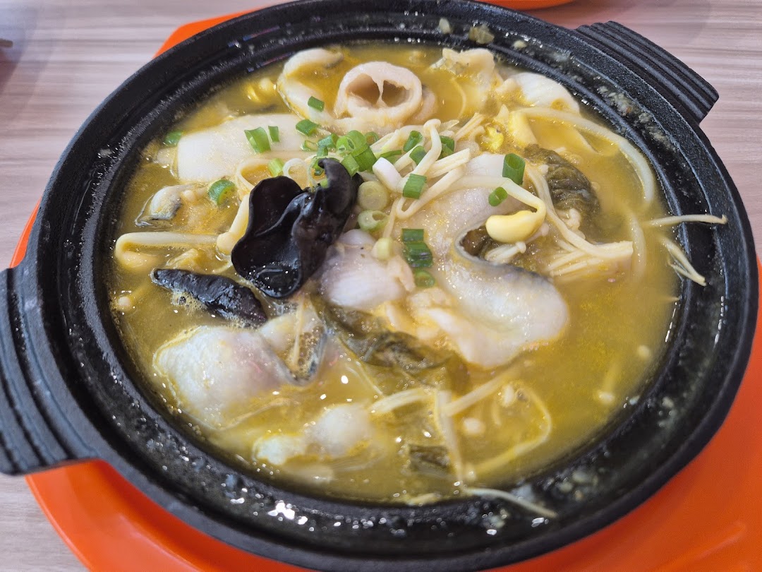 A close-up of a delicious fish soup with mushrooms and vegetables served in a black pot.