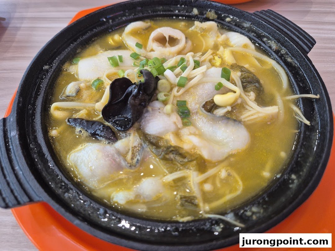 A close-up of a delicious fish soup with mushrooms and vegetables served in a black pot.