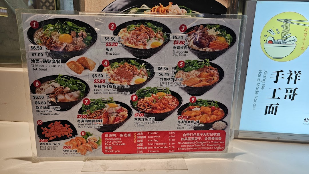 A detailed menu board displaying various noodle dishes, prices, and add-ons from a food stall.