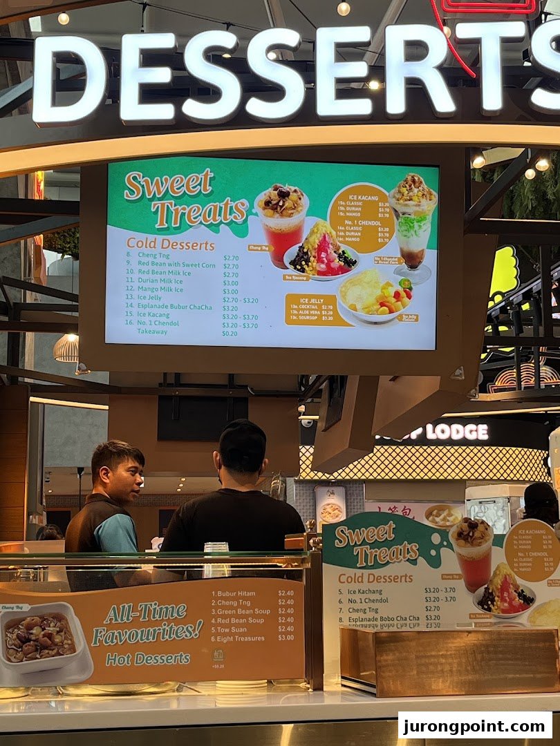 A dessert counter at Kopitiam Food Hall featuring a digital menu board and staff.
