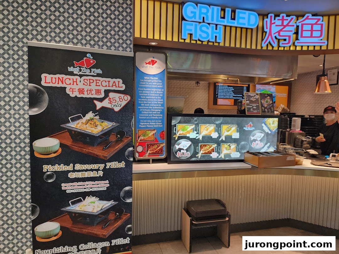 Interior view of 'What The Fish' food stall, featuring promotional banners and a service counter.